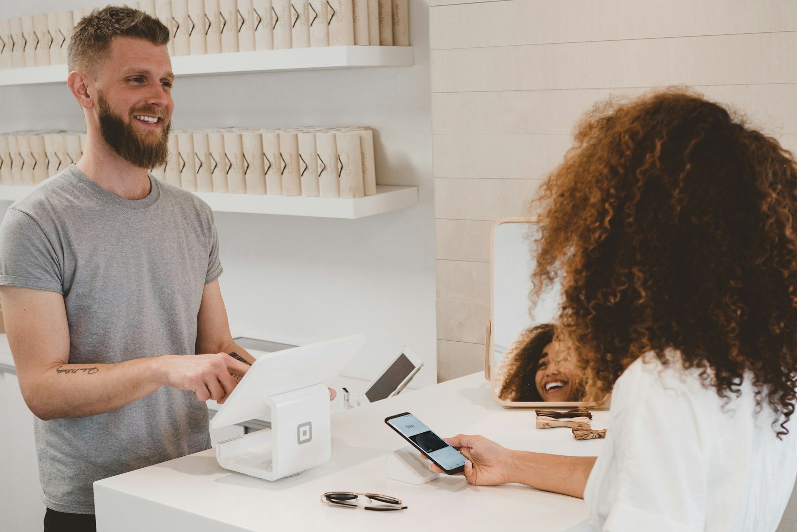 A shop owner smiling while helping a customer at the counter